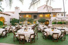 an outdoor dining area with tables, chairs and white tablecloths on the grass