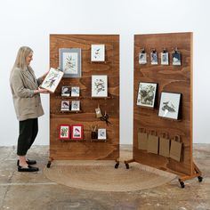 a woman standing next to two wooden boards with pictures on them and holding a book