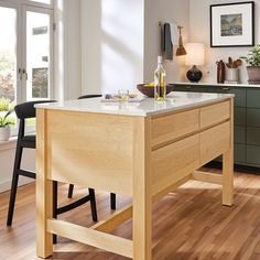 a kitchen island with marble top and wooden legs in front of an open doored window