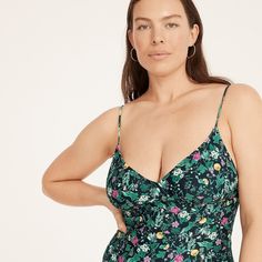 a woman in a green floral print swimsuit with her hands on her hips, looking at the camera