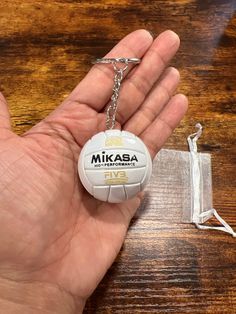 Introducing a miniature  Mikasa volleyball with ridges, designed to be a charming accessory for your backpack, keys, or as a rear view ornament. Crafted from sturdy hard leather like material, it features a durable silver keychain attachment. Additionally, it comes with an adorable white "net" pouch for safekeeping. This miniature volleyball is a must-have for volleyball players and enthusiasts alike. Volleyball Wishlist, Mikasa Volleyball, Volleyball Keychain, Volleyball Accessories, Volleyball Practice