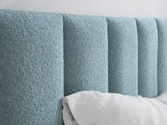 the headboard of a bed with blue sheets and pillows