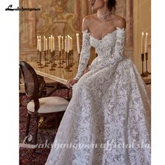 a woman in a white wedding dress sitting on a table with candles behind her and wearing a tiara