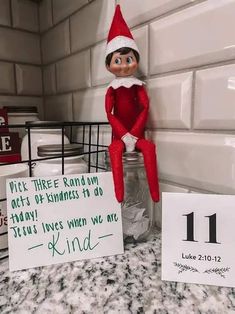 an elf is sitting on top of a mason jar next to a sign that says, pick three random out of happiness to do today's lives when we are kind of kind