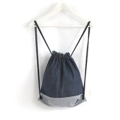 a denim bag hanging on a hanger against a white wall, with the back pocket open