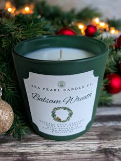 a candle sitting on top of a wooden table next to christmas decorations and baubles