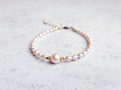 This gorgeous bracelet is made from natural rice shaped pink freshwater pearls with a round AAA grade pink pearl at the center framed by vermeil beads.  The pearls are dainty and distinctively pink, perfect for stacking with any bracelets from my shop! All finishings are gold filled, making the bracelet tarnish resistant and suitable for everyday wear. The length is 6.5 inches with 1 inch extension chain. Please message me if you need a customized size or without extension chain, I need to confi Adjustable Pink Pearl Bracelet With Pearl Drop, Pink Pearl Bracelet Gift, Pink Pearl Drop Bracelet, Elegant Pink Pearl Bracelet As A Gift, Elegant Pink Pearl Bracelet For Gifts, Elegant Pink Pearl Bracelet Gift, Elegant Pink Pearl Bracelet, Elegant Pink Bracelet With Pearl Charm, Pink Pearl Drop Bracelet As Gift