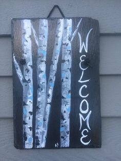 a wooden sign hanging on the side of a building with white birch trees painted on it