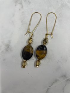 🐯 Tiger Eye Earrings with 22k Gold 🐯 Elevate your style with these exquisite Tiger Eye Earrings set in 22k gold. Handcrafted with stunning tiger eye gemstones, these earrings capture the rich, earthy tones and natural beauty of the stones, beautifully complemented by the luxurious 22k gold setting. Perfect for adding a touch of elegance and sophistication to any outfit, these earrings are a must-have for any jewelry lover. ✨ Features: Design: Beautiful tiger eye gemstones set in elegant 22k go Gold Dangle Gemstone Linear Earrings, Gold Gemstone Drop Crystal Earrings, Elegant Gold Hoop Earrings With Natural Stones, Gold Gemstone Linear Earrings Gift, Gold Gemstone Drop Danglers, Gold Linear Gemstone Earrings As A Gift, Gold Earrings With Natural Stones, Gold Earrings With Natural Stones For Gift, Gold Dangle Earrings With Natural Stones