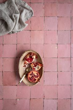 pomegranates in a bowl on a pink tiled floor