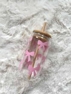 a pink and white cup sitting on top of a fur covered floor next to a wooden stick