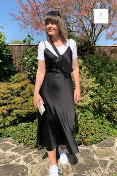 To get more wear out of your black slip dress, try styling with a bodysuit and trainers. Here I've teamed it up with a hip bag by INYATI for a more casual yet contemporary outfit. Monochrome styling is so chic, it's perfect for a daytime city trip, travelling outfit or simple brunch date  with girlfriends. #daytimestyling #blackslipdress #slipdress #brunchoutfit #travelchic #citystyle Daytime City Outfit Summer, T Shirt Slip Dress, Dress Down Silk Dress, Black Silk Dress Slip, Slip Dress And Converse, Satin Dress And T Shirt, Satin Long Dress Outfit, Black Satin Dress Casual Outfit, Monochrome Dress Outfit