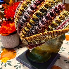 a crocheted hat sitting on top of a table next to other colorful flowers