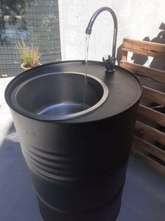 a large black barrel with water running from it's faucet to the side