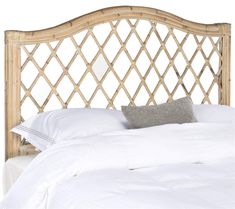 a bed with white linens and a bamboo headboard