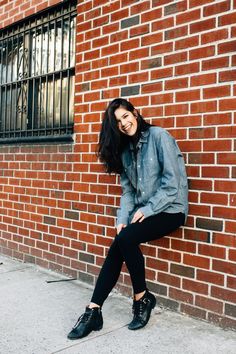 a woman is leaning against a brick wall