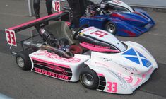 two race cars with pink and blue paint sitting on the ground next to each other