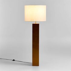 a floor lamp with a white shade on it and a cord plugged into the base