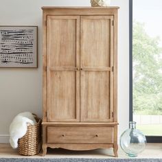 a wooden armoire sitting next to a vase on top of a rug in a living room