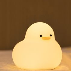 a little white light sitting on top of a bed next to a stuffed animal toy