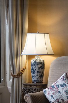 a blue and white vase sitting on top of a table next to a lamp in a living room