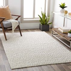 a living room with a white rug, chair and potted plant in the corner