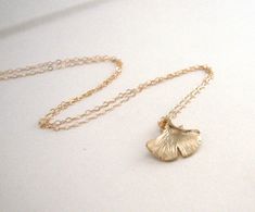 "A gorgeous gold ginkgo leaf hangs from a beautiful 14k Gold-Filled chain. The ginkgo shape and shade of gold are so pretty in this pendant. Leaf is textured on either side. - Pendant - Matte Gold plated brass - 14mm x 16mm - Chain + components - 14K Gold Fill - Clasp - 14K Gold-Filled lobster clasp . . . . . . . . . . . . . . . . . . . . . . . . . . . . . . . . . Want more for bridesmaids, sisters or friends? I am happy to put custom orders together! . . . . . . . . . . . . . . . . . . . . . . Delicate Gold Leaf-shaped Jewelry, Delicate Petal-shaped Gold Jewelry, Leaf Necklace Gold, Leaf Necklace Silver, Gold Leaf Necklace, Woodland Jewelry, Golden Necklace, Ginkgo Leaf, Shades Of Gold