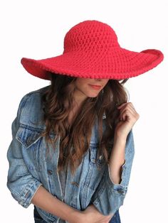 a woman wearing a red hat and denim jacket with her hands in her pockets,