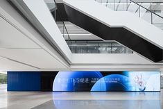 an empty lobby with large screen displays in the center and stairs leading up to it