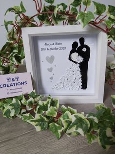 a paper cutout of a bride and groom holding each other in a white frame