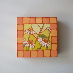 an orange and yellow square with flowers painted on it