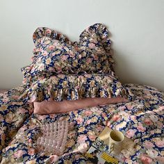 an unmade bed with pink and blue floral bedspread on top of it