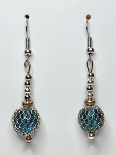 PRODUCT STYLE:     Dangle Earrings  DESCRIPTION: These fun dangle earrings are made of blue swirl glass beads and blue glass bead with mesh wrapped around it. Blue Wire Wrapped Dangle Earrings, Blue Round Crystal Earrings In Metal, Blue Metal Beaded Earrings Wire Wrapped, Blue Metal Beaded Drop Earrings, Blue Metal Beaded Earrings, Blue Beaded Metal Earrings, Blue Metal Beaded Earrings For Pierced Ears, Blue Metal Beaded Earrings For Party, Blue Wire Wrapped Beaded Metal Earrings