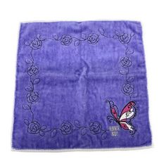 a purple towel with an embroidered butterfly and roses on the front, sitting on a white surface