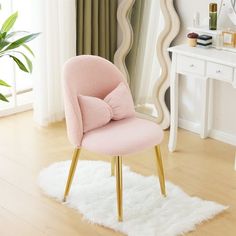 a pink chair with a bow on it in front of a mirror and white rug