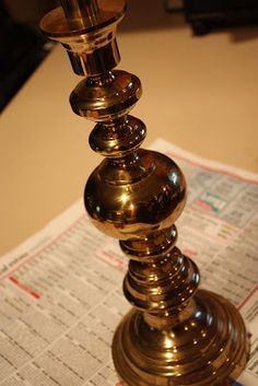 a metal candle holder sitting on top of a newspaper