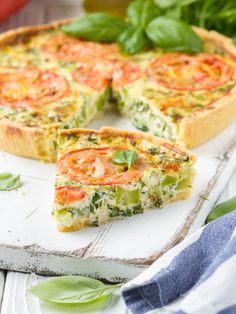 a quiche with tomatoes and spinach on a cutting board