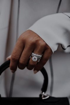 a person holding onto a black handbag with a diamond ring on it's finger