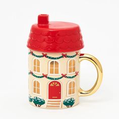 a ceramic coffee mug with a red lid and a house design on it, sitting against a white background