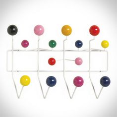 an assortment of colorful balls and pegs on a white wall mounted rack against a white background