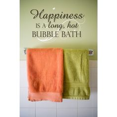 two towels hanging on a towel rack in front of a wall with the words happiness is a long, hot bubble bath