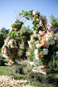 two large vases filled with flowers sitting on top of a lush green field