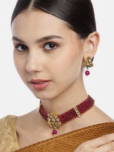 This beautiful jewelry set consists of a handcrafted choker necklace and a pair of matching earrings. The maroon multi-layer stones & beaded choker necklace shown here comes with kundan stone studs, is gold-plated, and secured with an adjustable drawstring closure. A pair of matching oversized circular studs come secured with a post and back closure. This gorgeous statement piece can add impact to any outfit for any festive occasion! Product color may vary based on the monitor or screen you are Heavy Temple Jewelry Choker Sets, Adjustable Chandbali Jewelry With Stone Work, Bollywood Beaded Choker For Diwali, Adjustable Temple Style Kundan Necklace, Festive Temple Jewelry Choker For Parties, Adjustable Festival Choker Jewelry, Festive Choker For Celebration, Gold Jeweled Kundan Choker Necklace, Festive Kundan Choker Necklace With Jeweled Details