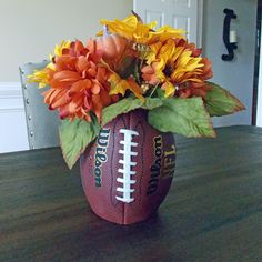 a football vase with flowers in it sitting on a table next to a door way