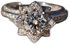 an engagement ring with two matching bands and a flower shaped diamond in the center, surrounded by round brilliant cut diamonds