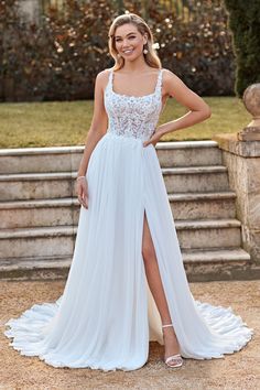 a woman wearing a white wedding dress standing in front of some steps with her hand on her hip