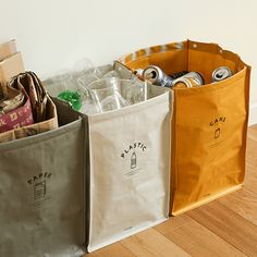 three canvas bags sitting on top of a wooden floor next to each other with soda cans in them