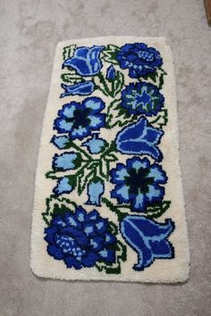 a rug with blue flowers on it laying on the floor next to a wooden stick