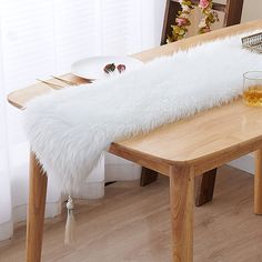 a table with a white furry bench cover on it and a glass of wine next to it