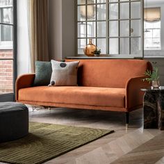 an orange couch sitting in front of a window